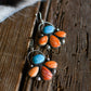 Pair of earrings with turquoise and orange stones on a wooden surface
