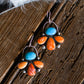 Pair of earrings with turquoise and orange stones on a wooden surface