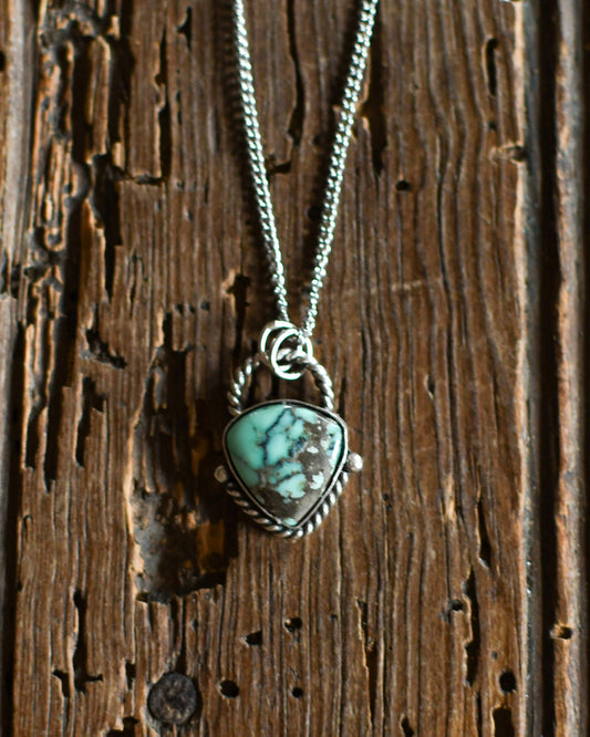 Silver necklace with green stone on rustic wooden background