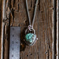 Necklace with a turquoise pendant on a wooden surface next to a ruler for scale.
