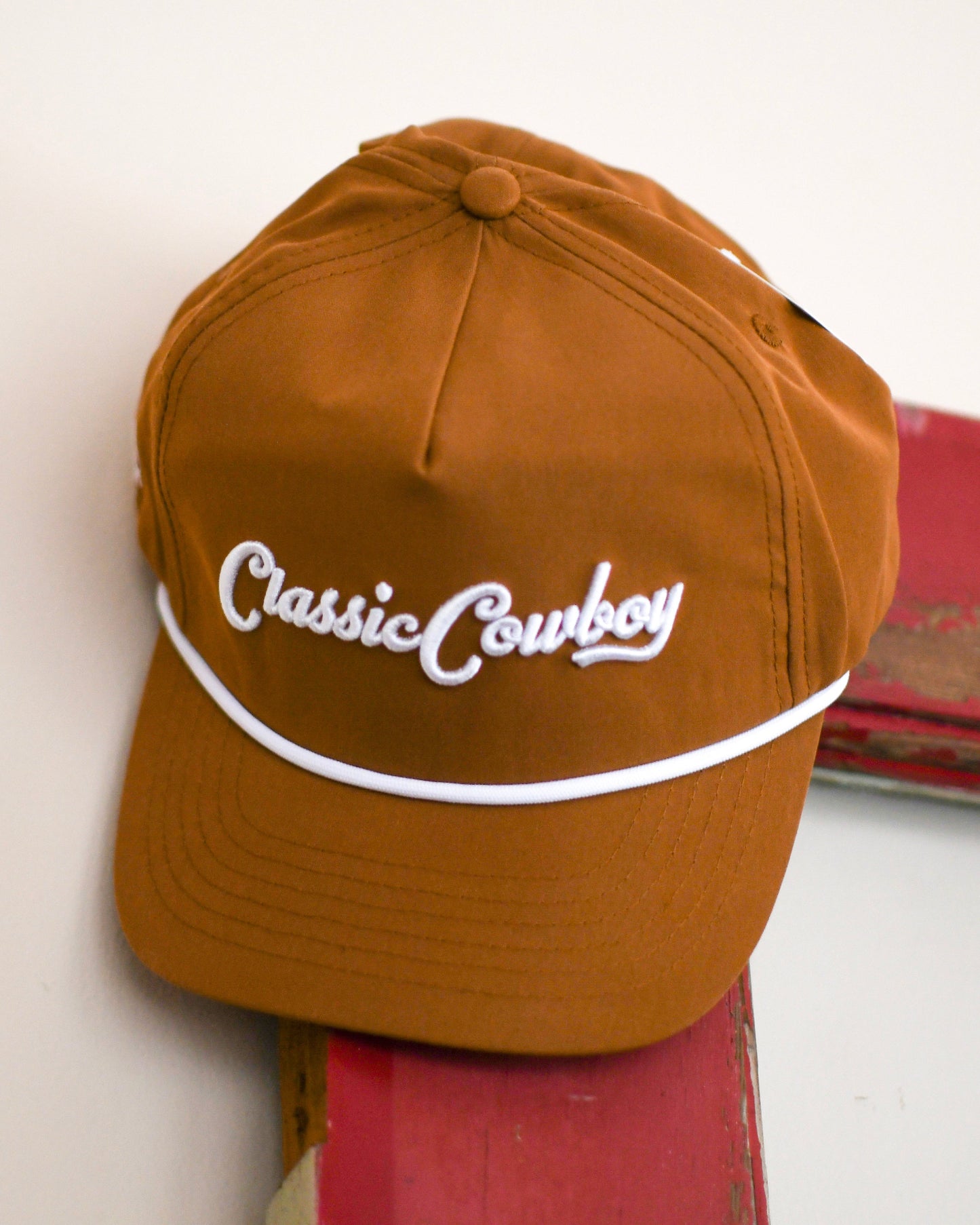 close up of hat hanging on door with white background