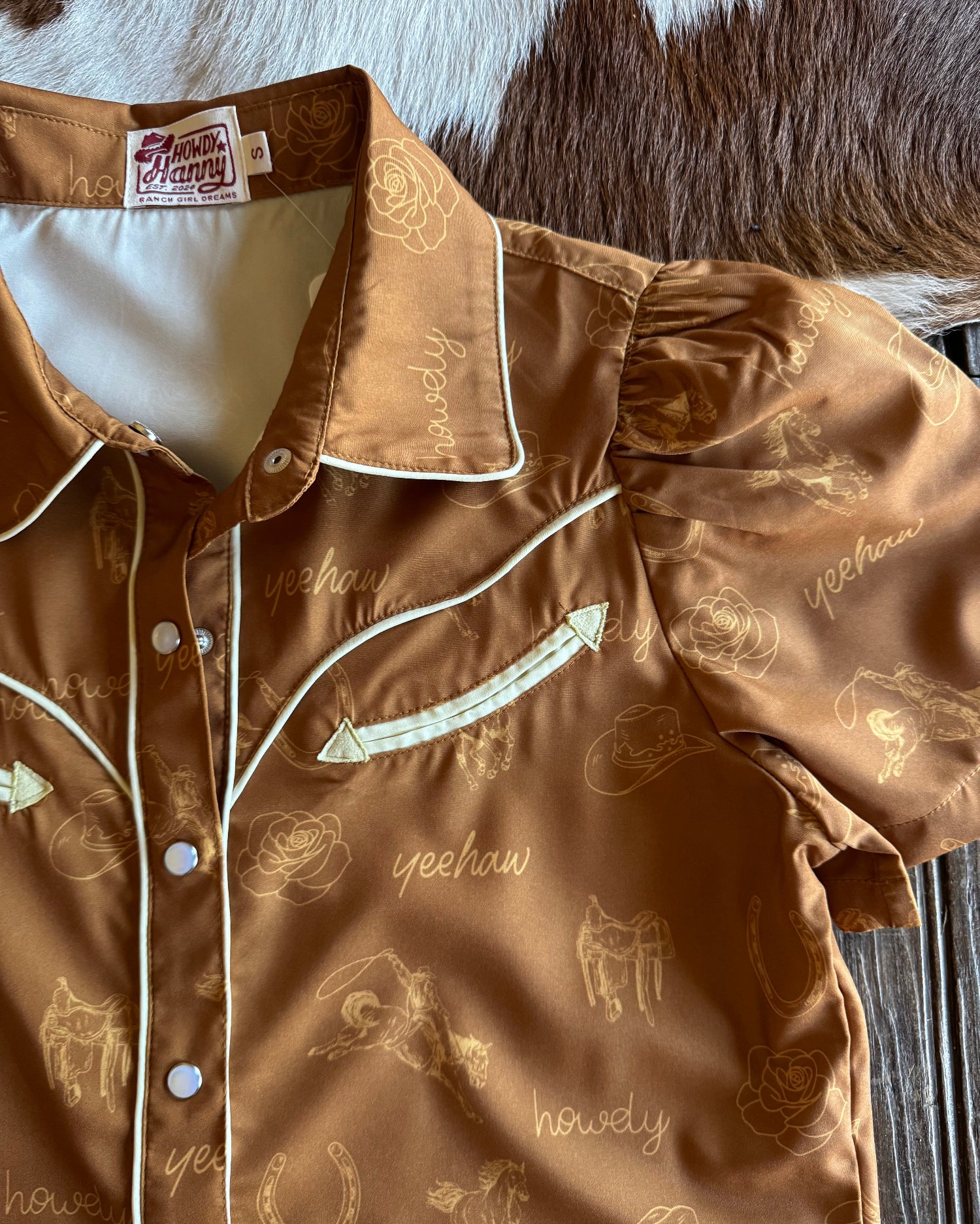 Brown shirt with designs on a wooden surface
