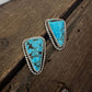 Pair of turquoise stone earrings on a wooden surface