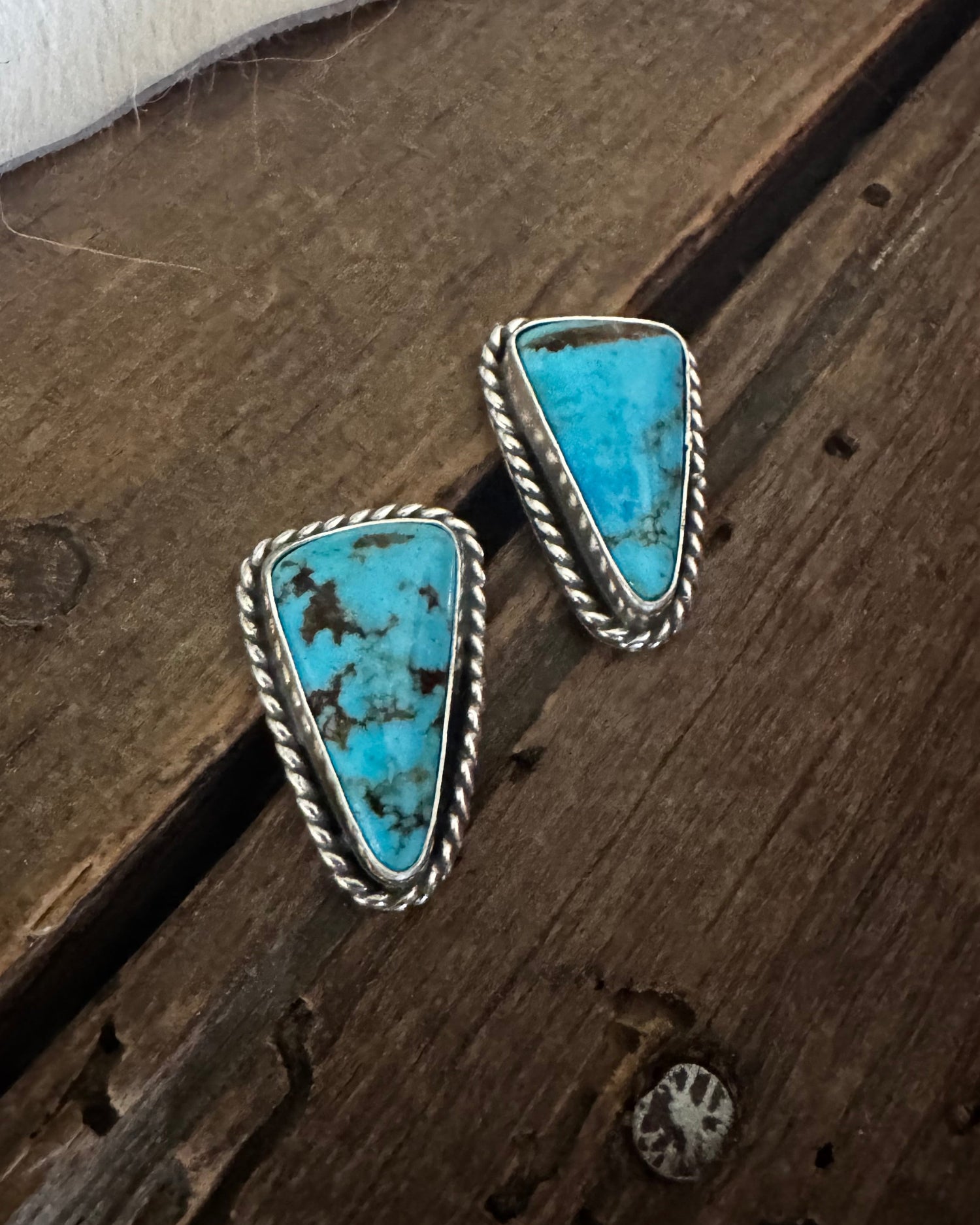 Pair of turquoise stone earrings on a wooden surface