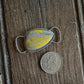 Silver twilly slide with yellow stone next to a quarter on wooden surface