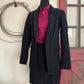 Black coat with pink shirt on a mannequin against a neutral background