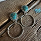 Silver hoop earrings with turquoise stones on a wooden surface