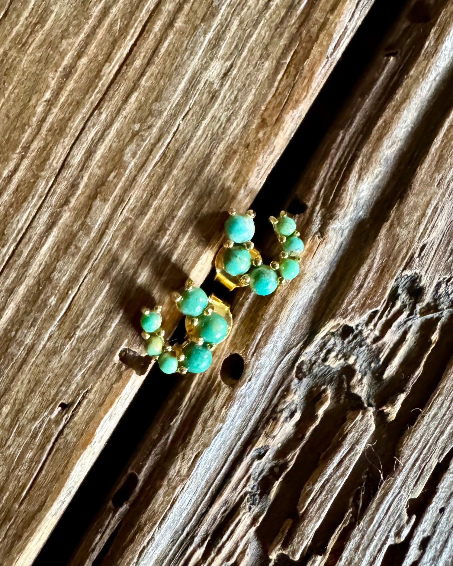 turquoise and gold horse shoe earrings on wooden background 