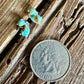 Stud earrings with double turquoise stones on a wooden background with a quarter