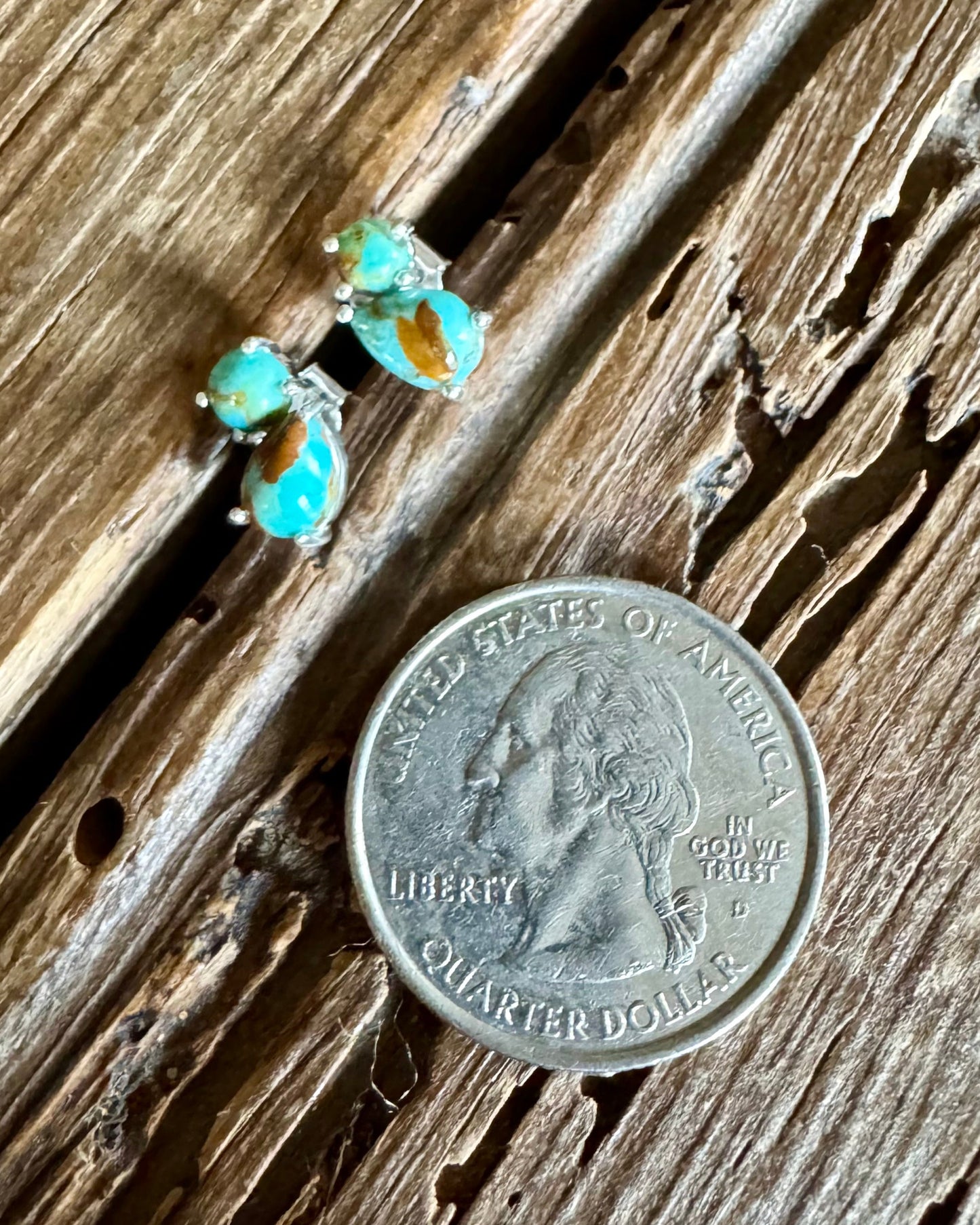 Stud earrings with double turquoise stones on a wooden background with a quarter