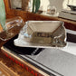 Silver tray on top of books with a blurred indoor background