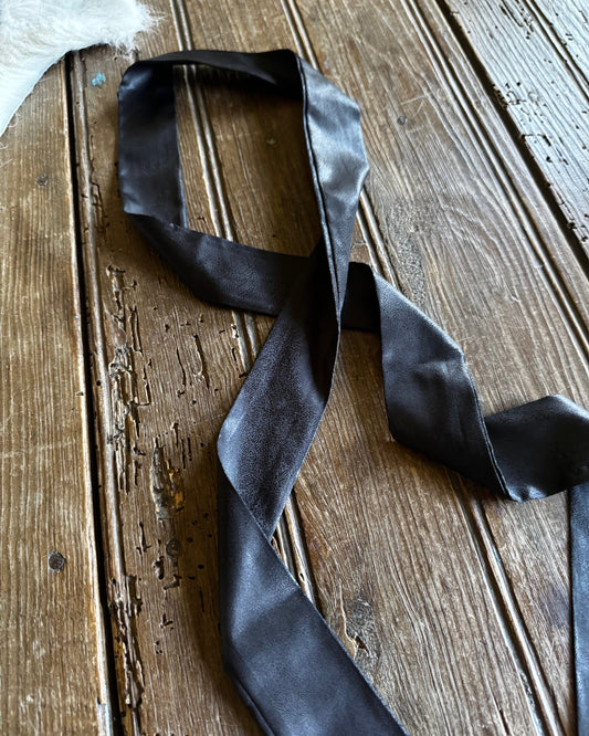 Black satin ribbon on a wooden surface