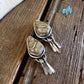 Pair of silver earrings with stone inlays on a wooden surface