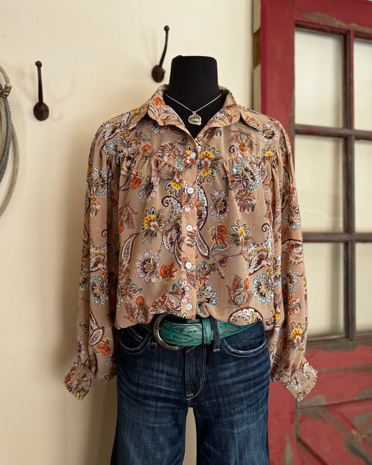Mannequin wearing a patterned shirt and jeans against a wall with hooks.