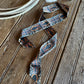 Ribbon scarf with horseshoes on a rustic wood background with a cowhide and rope