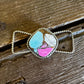 Twilly slide with a multicolored stone pendant on a wooden surface