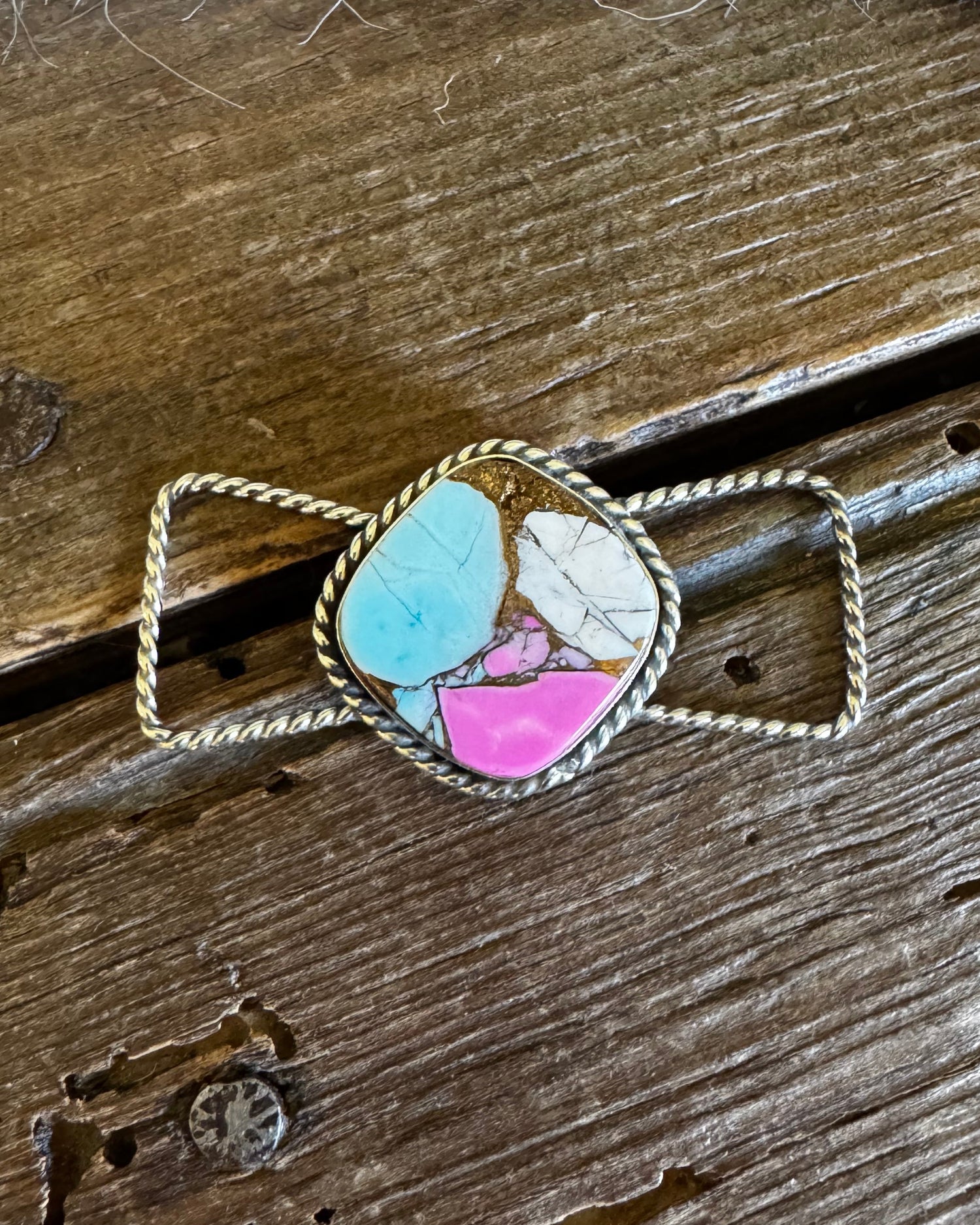 Twilly slide with a multicolored stone pendant on a wooden surface