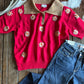Red sweater with floral patterns and blue jeans on a wooden surface