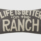 Decorative pillow with 'Life is better on the ranch' text on a plain background