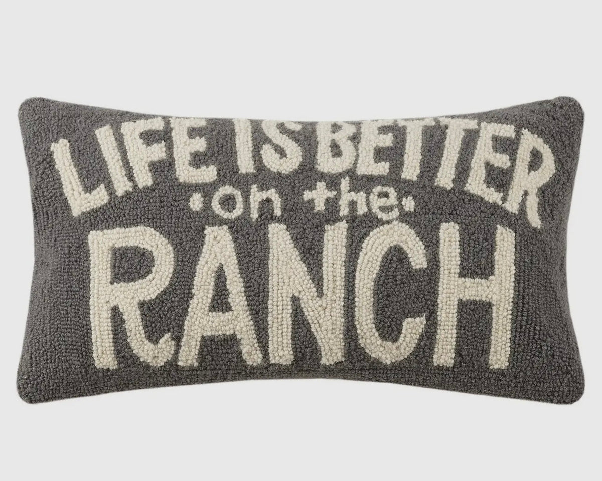 Decorative pillow with 'Life is better on the ranch' text on a plain background