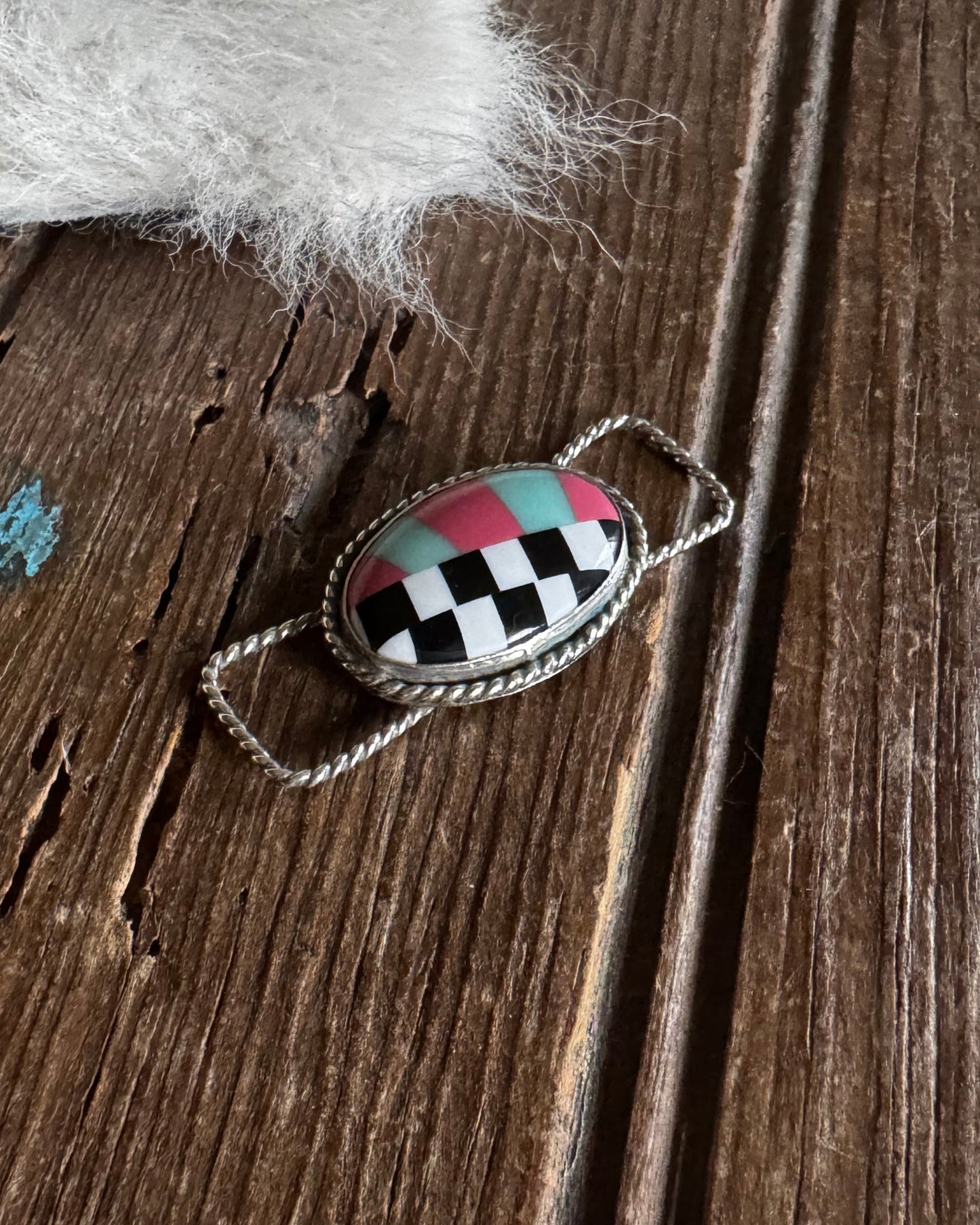 Checkered twilly slide on a wooden surface with horse hair visible