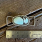 Silver twilly slide with turquoise stone next to a ruler on a wooden surface