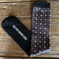 Black sock with 'Red Bar N' logo and patterned tie on a wooden surface
