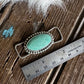 Turquoise pendant with silver frame on a wooden surface next to a ruler