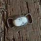Silver twilly slide with a white stone on a wooden surface