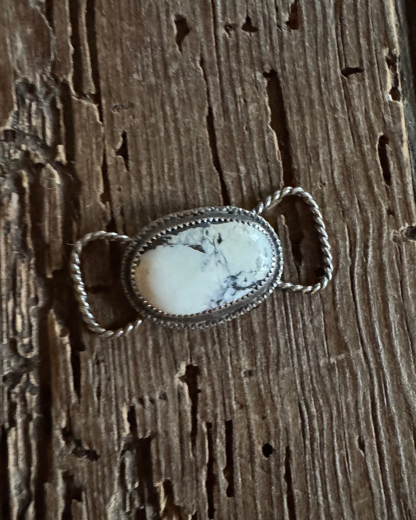 Silver twilly slide with a white stone on a wooden surface