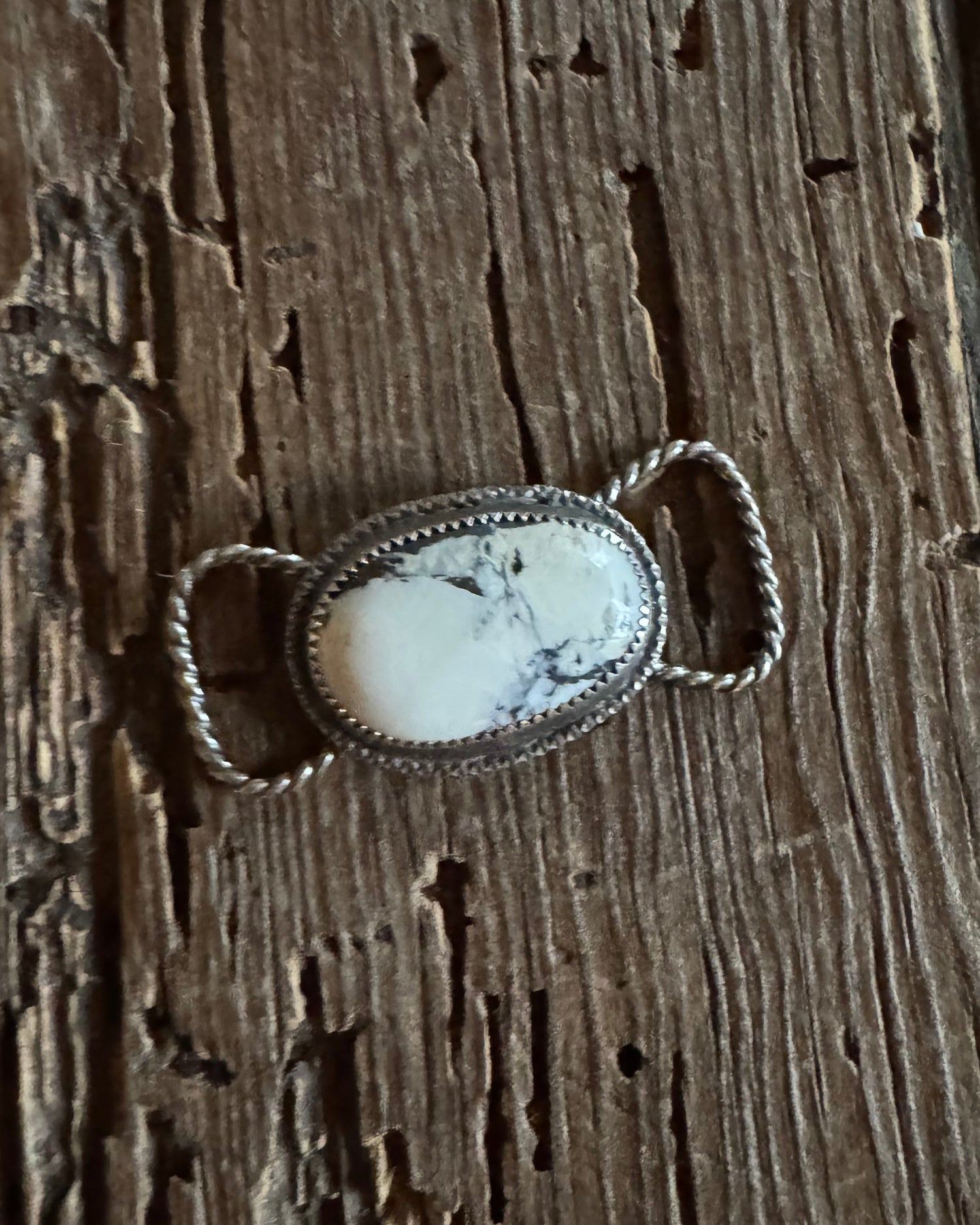 Silver twilly slide with a white stone on a wooden surface