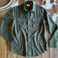 Green shirt on a wooden surface with a cowhide rug and rope in the background