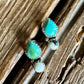 Turquoise and white buffalo stud earrings on a rustic wood background