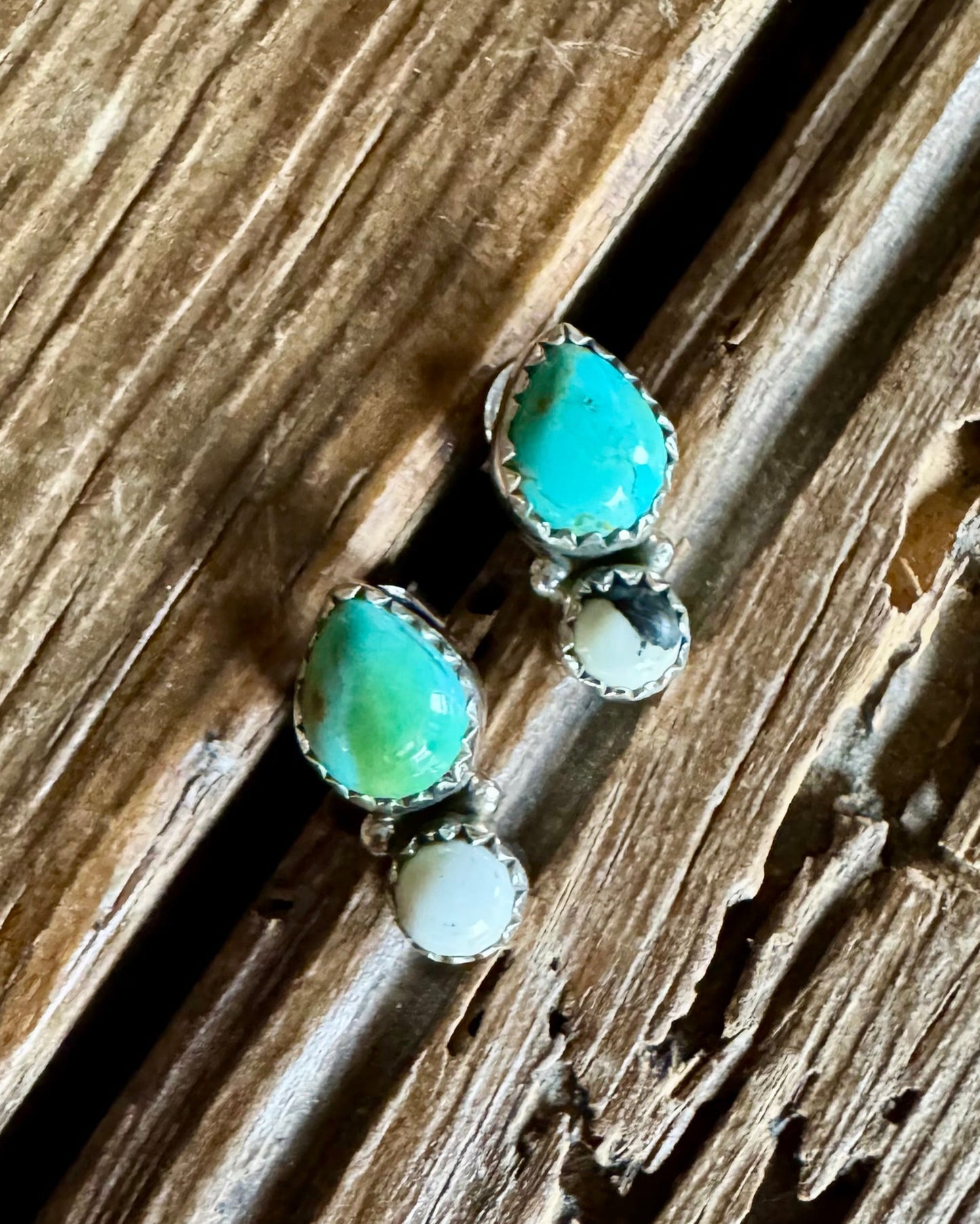 Turquoise and white buffalo stud earrings on a rustic wood background