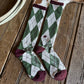 Green and white checkered socks with maroon accents on a wooden surface
