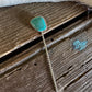 Turquoise pendant on a chain lying on wooden surface