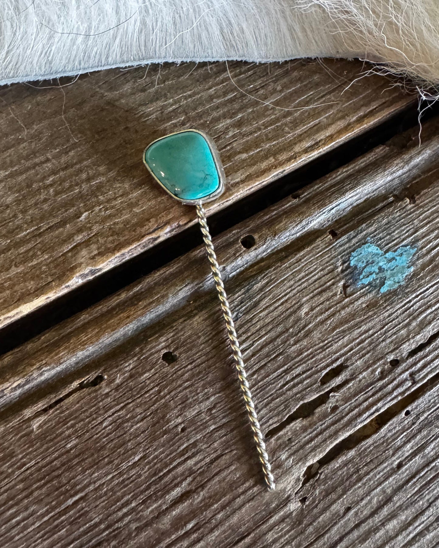 Turquoise pendant on a chain lying on wooden surface