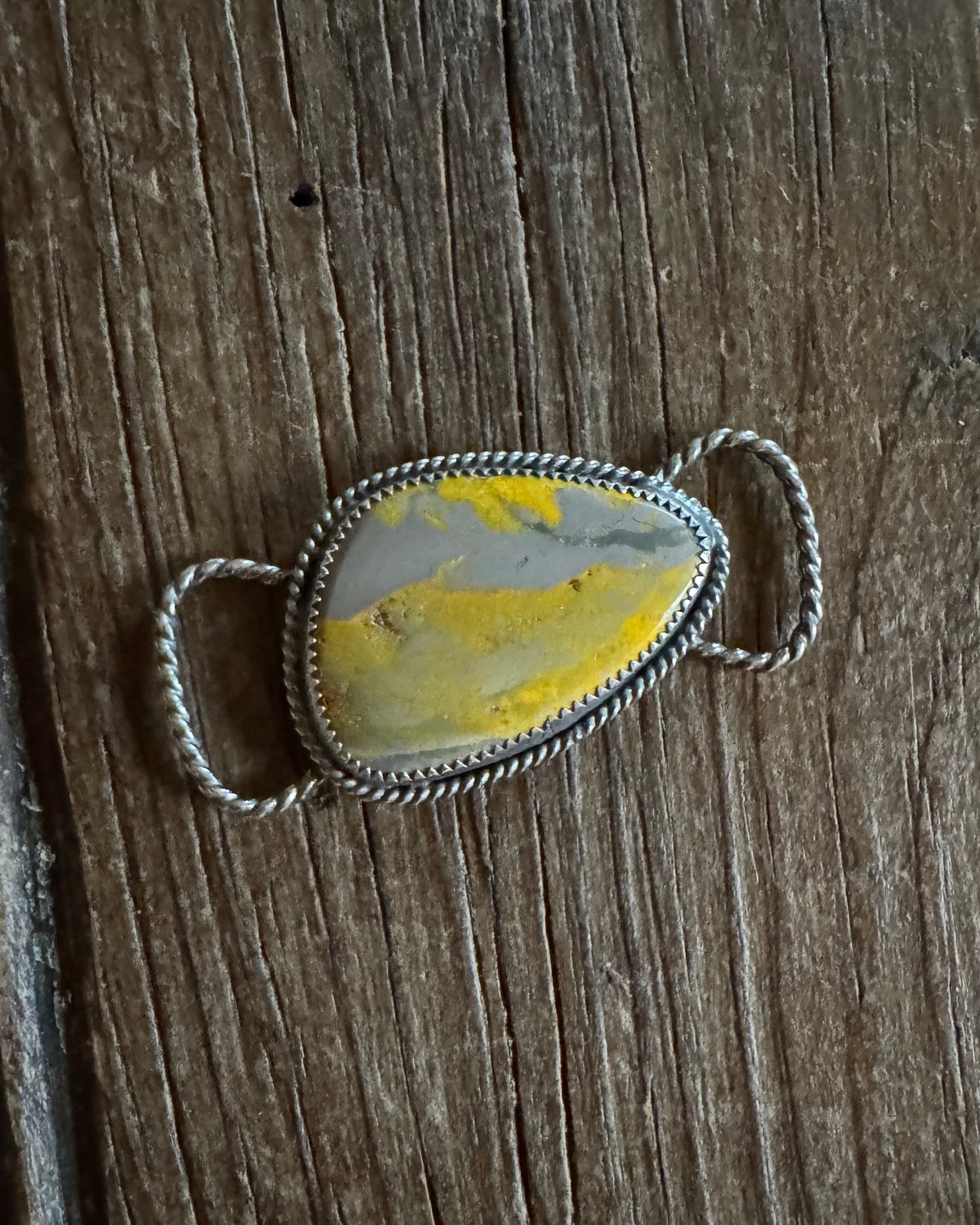 Silver twilly slide with a yellow stone on a wooden surface