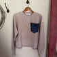 tan sweatshirt with a blue pocket on a white surface