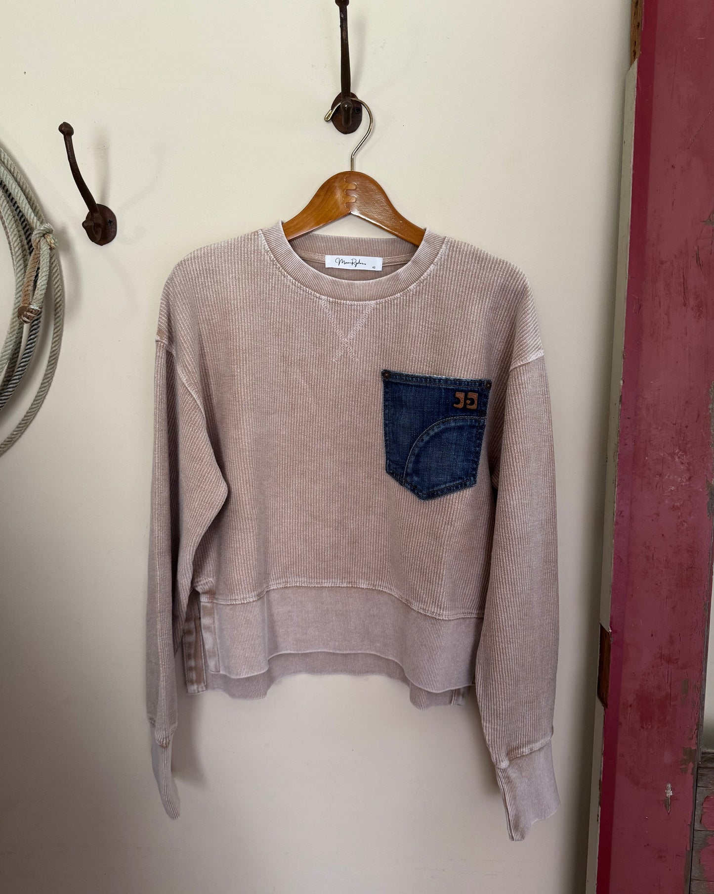 tan sweatshirt with a blue pocket on a white surface