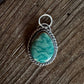 Turquoise stone pendant on a wooden surface