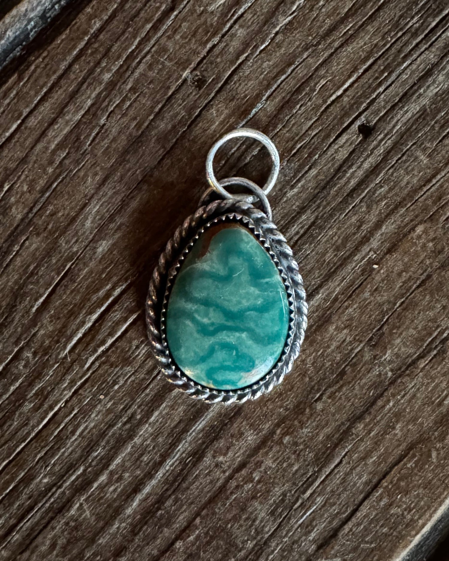 Turquoise stone pendant on a wooden surface