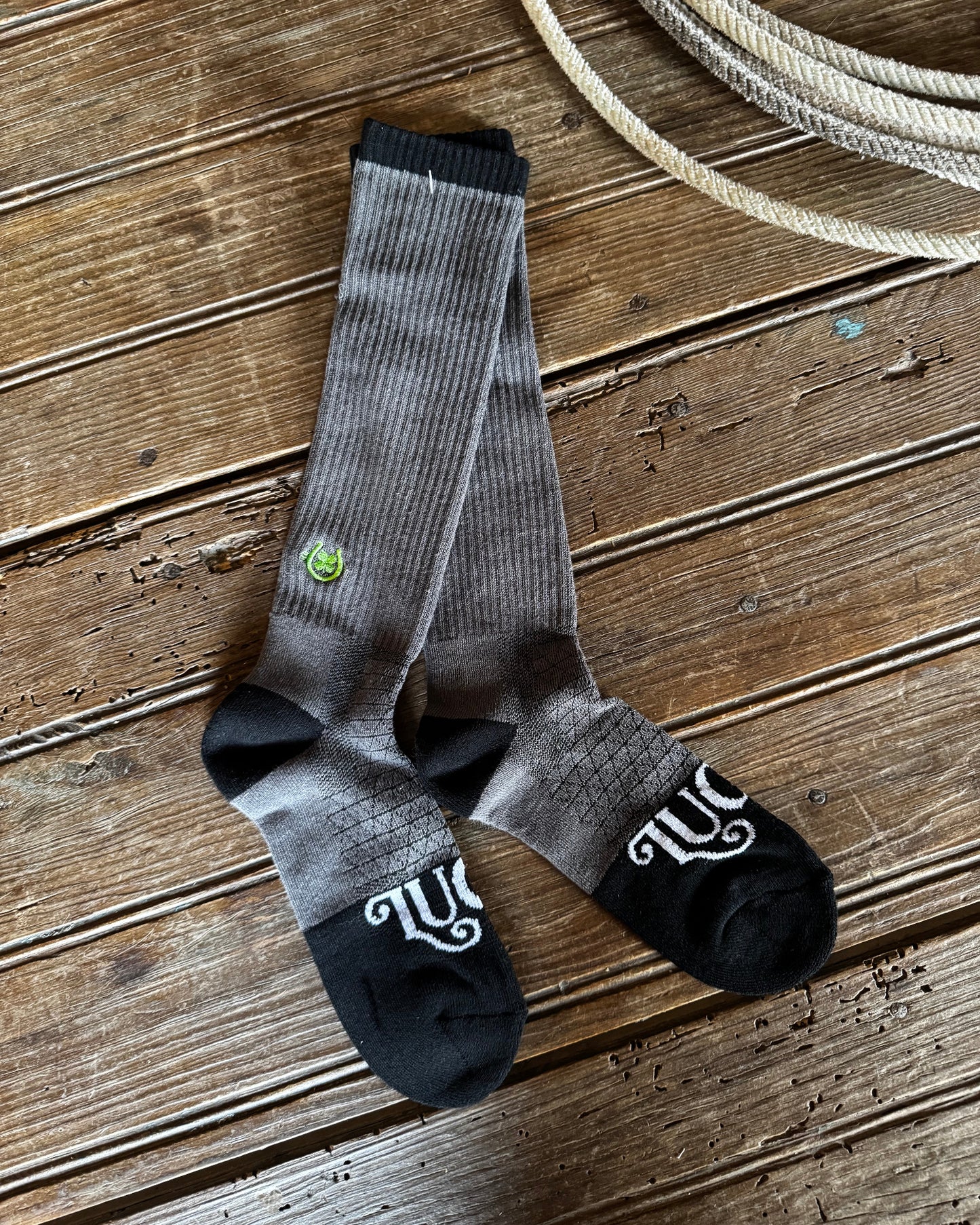 Gray and black socks with a logo on a wooden surface