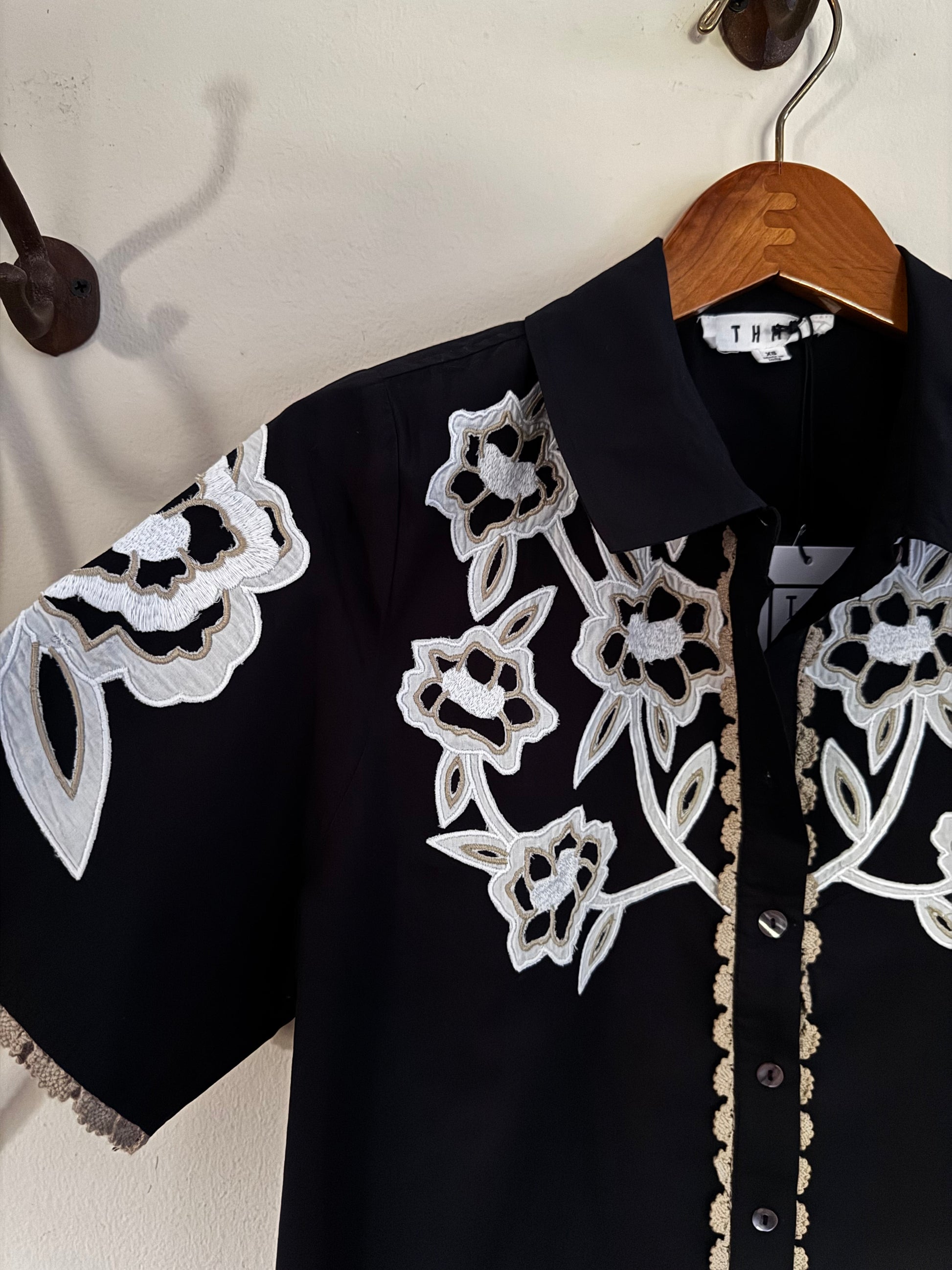 close up of floral embroidered blouse on white wall