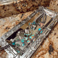 Silver and turquoise jewelry set on a decorative tray with a textured surface