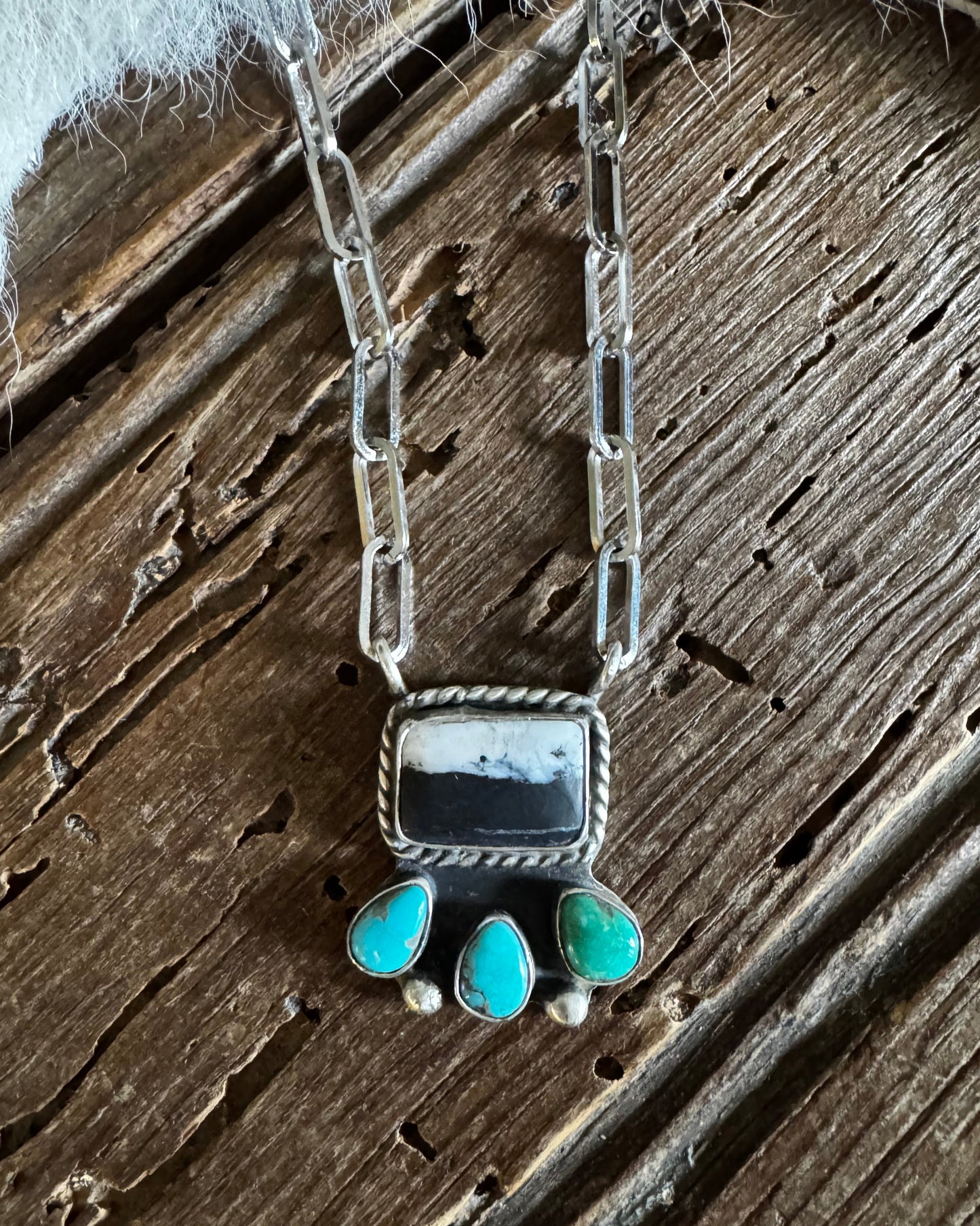 Silver necklace with turquoise stones on a wooden surface