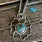 Necklace with a floral pendant featuring turquoise stone on a wooden surface
