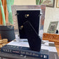 Black earrings in a clear display case on top of books with a cactus plant in the background.