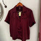 Maroon shirt on a hanger with a tag against a white background