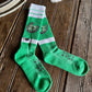 Green socks with white stripes on a wooden surface